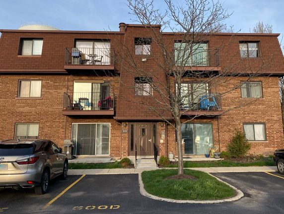 Front view of a three-story brick building with balconies.
