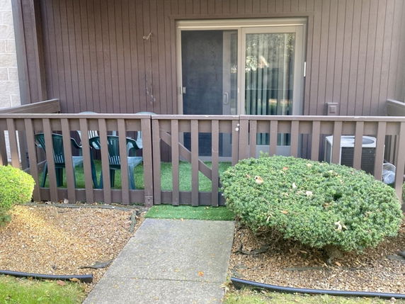 Front view of a building with a small patio area enclosed by a brown wooden fence.