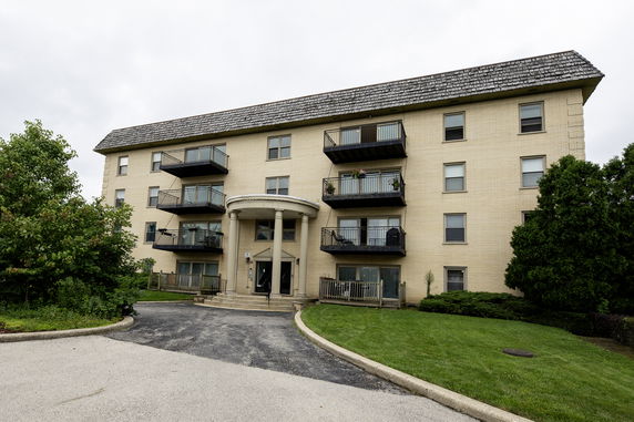 Front view of a four-story apartment building with balconies and a columned entrance.