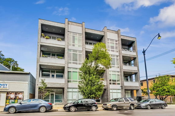 Front view of a modern multi-story apartment building with balconies and large windows.