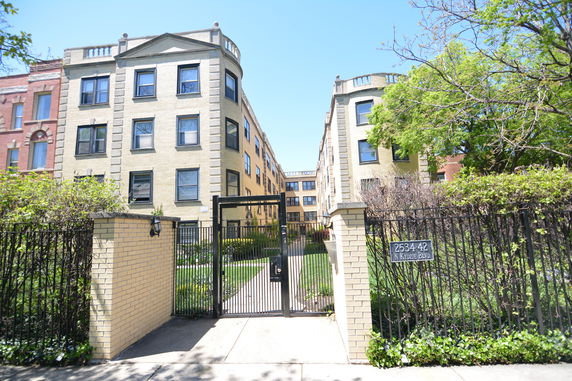 Front view of a multi-story residential building with a gated entrance.