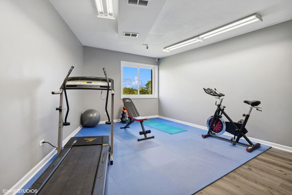 Indoor gym area with exercise equipment including a treadmill, exercise bike, and bench.