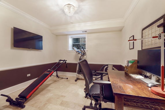 Indoor gym area with exercise equipment and a desk.