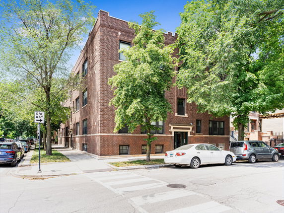 Front view of a multi-story brick building on a street corner.