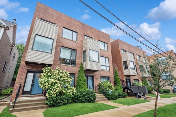 Front view of a modern three-story house with brick and siding exterior.
