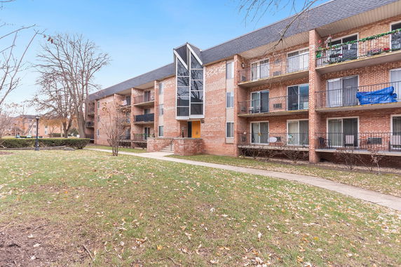 Front view of a multi-story brick apartment building with balconies.