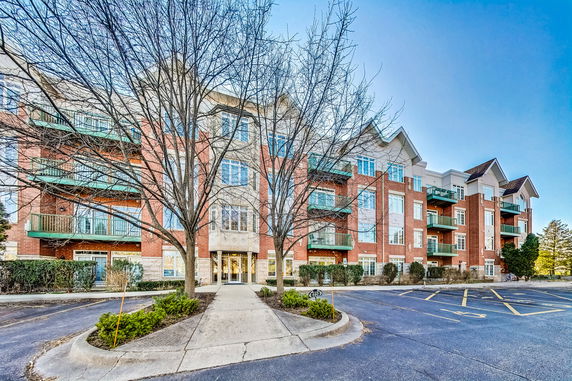 Front view of a multi-story residential building with balconies and a brick facade.