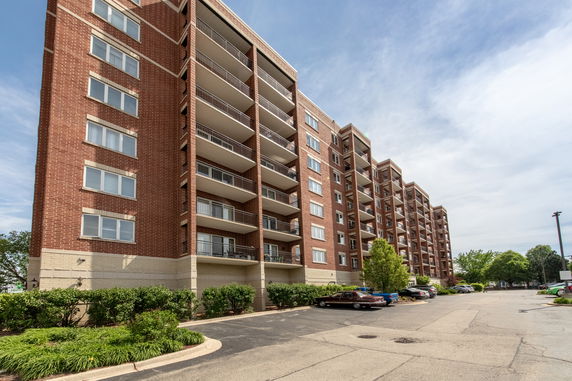 Front view of a multi-story brick apartment building with balconies.