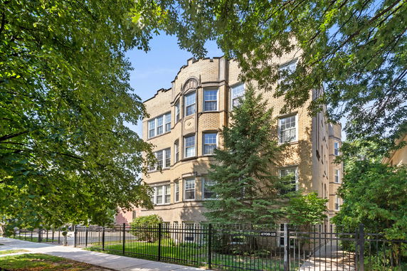 Front view of a multi-story brick apartment building with decorative windows.
