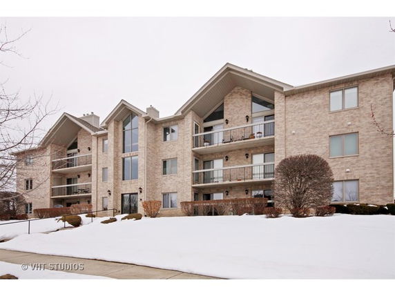 Front view of a multi-story apartment building with balconies and large windows.