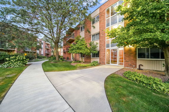 Front view of a multi-story brick apartment building with large glass entrance.