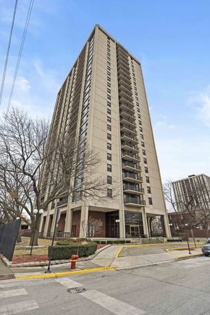 Front view of a tall residential building with multiple balconies.