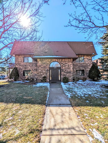 Front view of a brick two-story house with a brown roof.