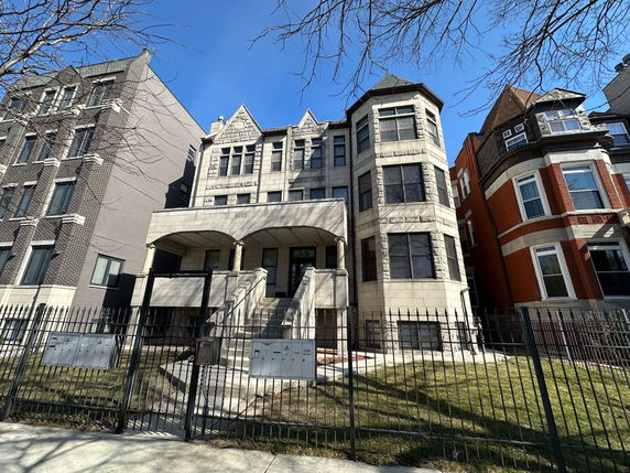 Front view of a multi-story house with a porch and staircase.