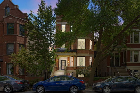 Front view of a multi-story brick house with steps leading to the entrance.
