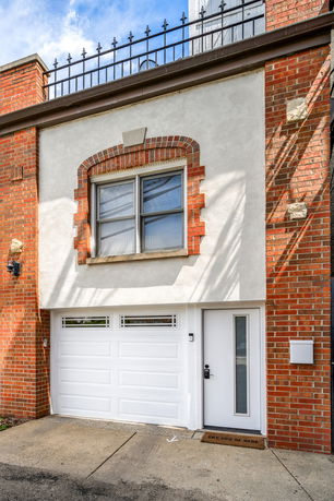 Front view of a building with a garage door and upper window.
