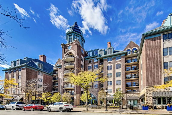 Front view of a multi-story brick building with balconies and a tower under a blue sky.