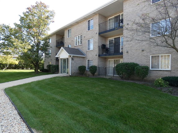 Front view of a multi-story brick residential building with balconies.
