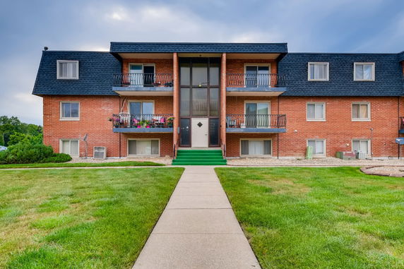 Front view of a multi-story brick apartment building with balconies.