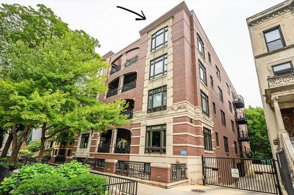 Front view of a multi-story brick building with balconies and gated entry.