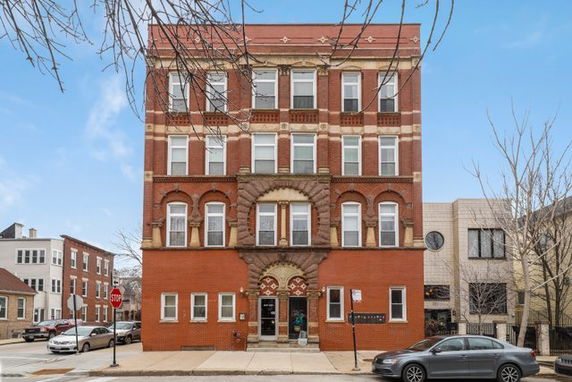 Front view of a four-story brick building with decorative arches around windows.