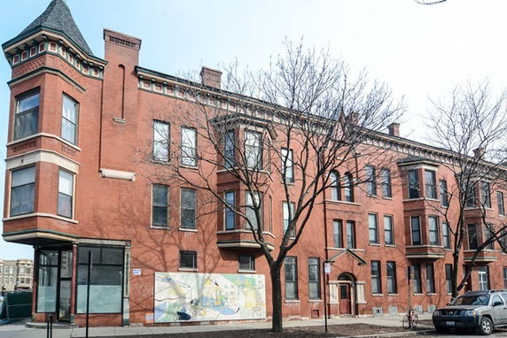 Front view of a multi-story brick building with multiple large windows.