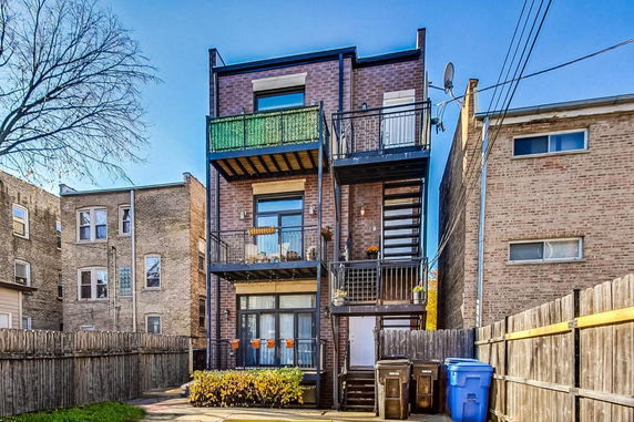 Rear view of a three-story brick building with balconies and exterior staircase.