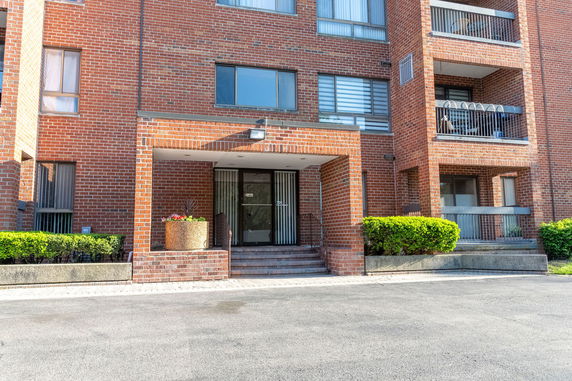 Front view of a brick apartment building with balconies and a main entrance.