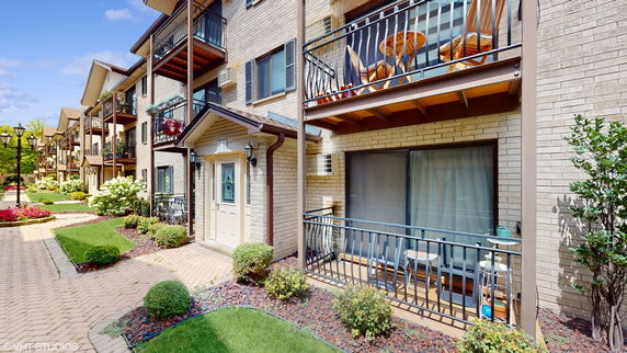 Front view of a multi-story apartment building with balconies and landscaped pathway.