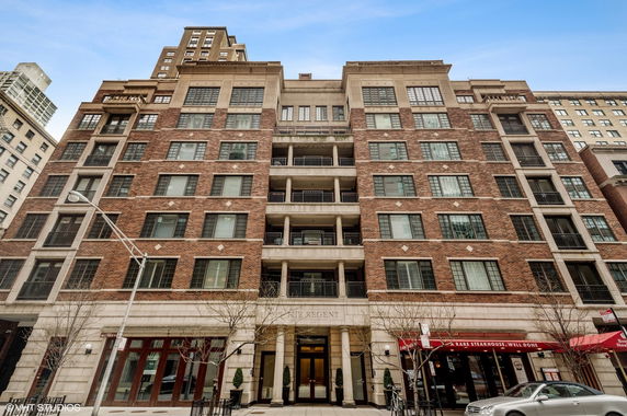 Front view of a multi-story building with brick facade and balconies.