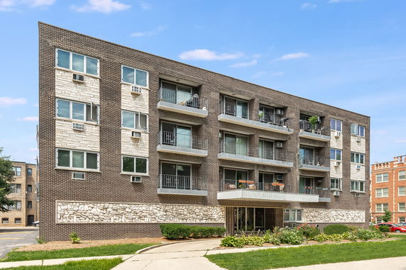 Front view of a multi-story brick apartment building with balconies.