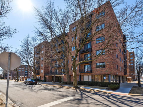 Front view of a multi-story brick apartment building on a street corner.