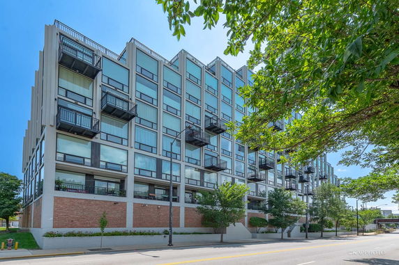 Front view of a modern multi-story building with large glass windows and balconies.