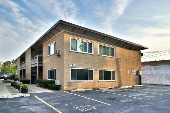 Front view of a two-story brick building with a flat roof and visible air conditioning units.