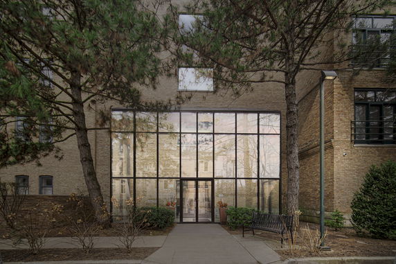 Front view of a building with large glass windows and trees in front.