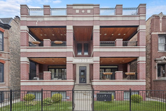Front view of a multi-story brick building with balconies and a central entrance.