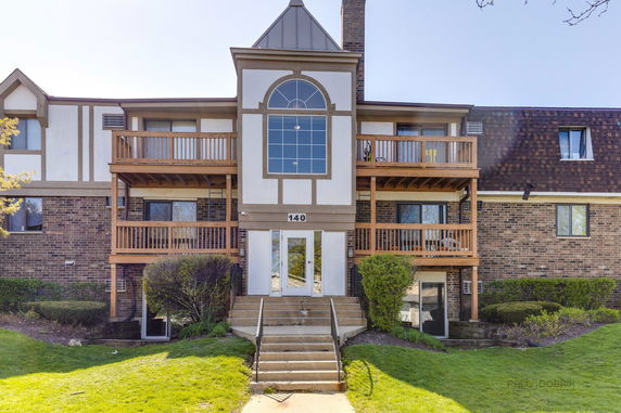 Front view of a multi-story building with wooden balconies and a central entrance.