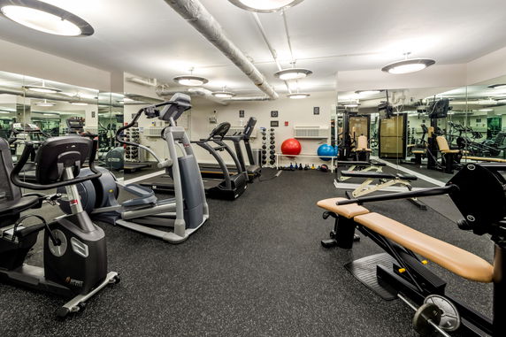 Interior of a gym with exercise equipment and mirrors.