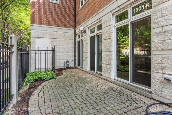 Exterior view of a brick and stone-faced building with glass doors leading to a paved patio.