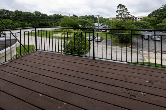 View from a balcony overlooking a parking lot and surrounding greenery.