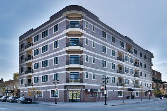 Front view of a multi-story apartment building with balcony railings and brick exterior.