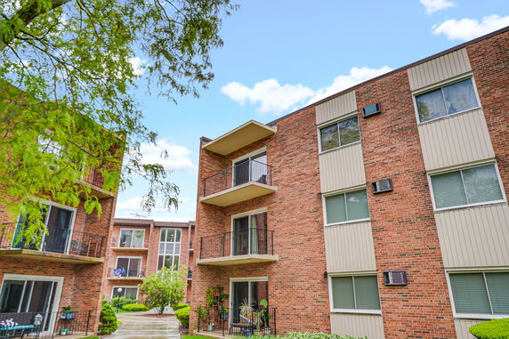 Front view of a multi-story brick apartment building with balconies.