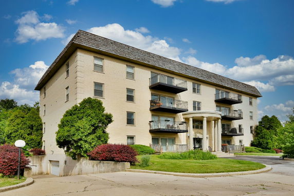 Front view of a multi-story apartment building with balconies and a tiled roof.