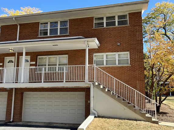 Front view of a two-story brick house with a staircase leading to the entrance and a double garage.