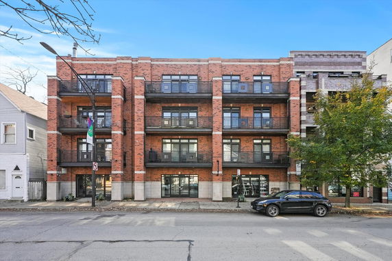 Front view of a multi-story brick apartment building with balconies on each floor.