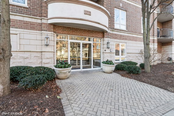 Front view of a building entrance with brick facade and glass doors.