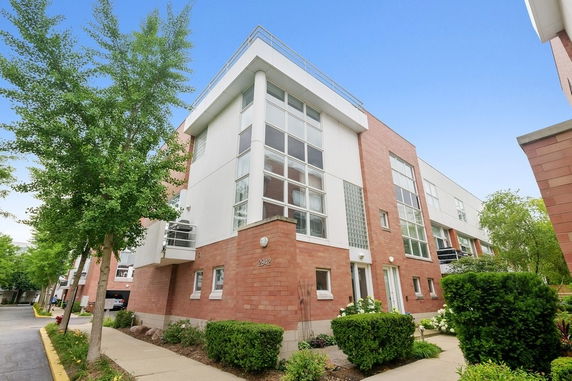 Front view of a modern multi-story building with large windows and brick facade.