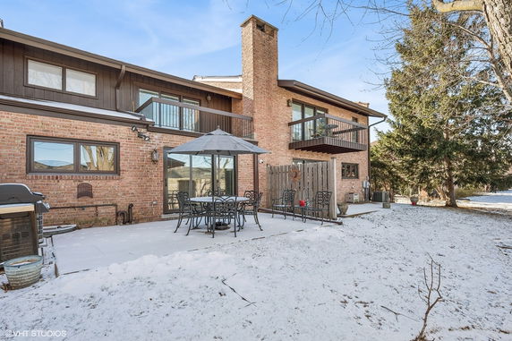 Rear view of a two-story brick house with balconies and a patio.