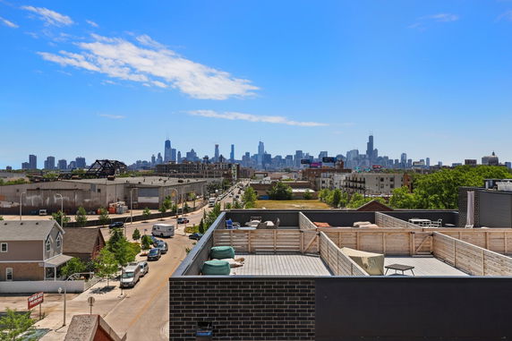 Panoramic view of a city skyline from a rooftop with outdoor seating.