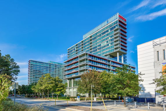 Front view of a modern multi-story building with extensive glass and balconies.